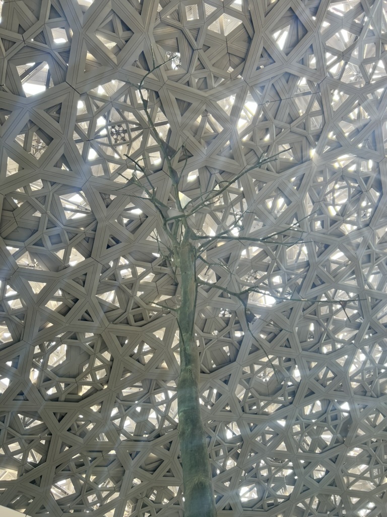 A tree rising beneath an intricate geometric lattice canopy