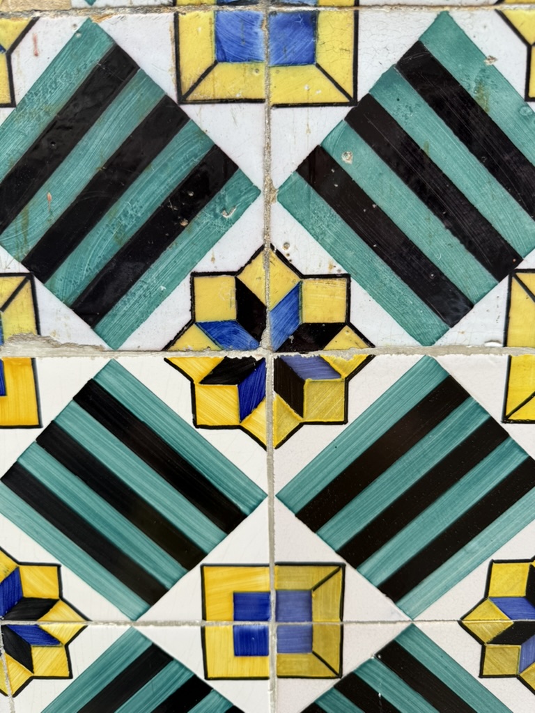 Green, black, blue, and yellow geometric tiles photographed in Portugal