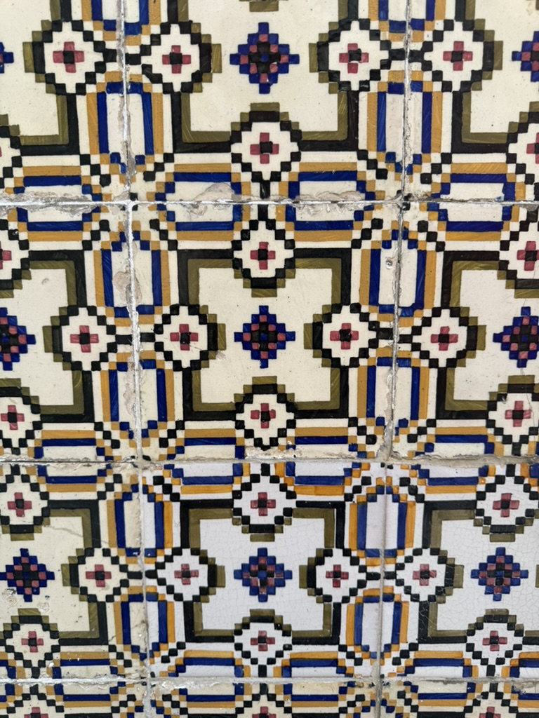 Geometric blue, ochre, and black ceramic tile photographed in Portugal